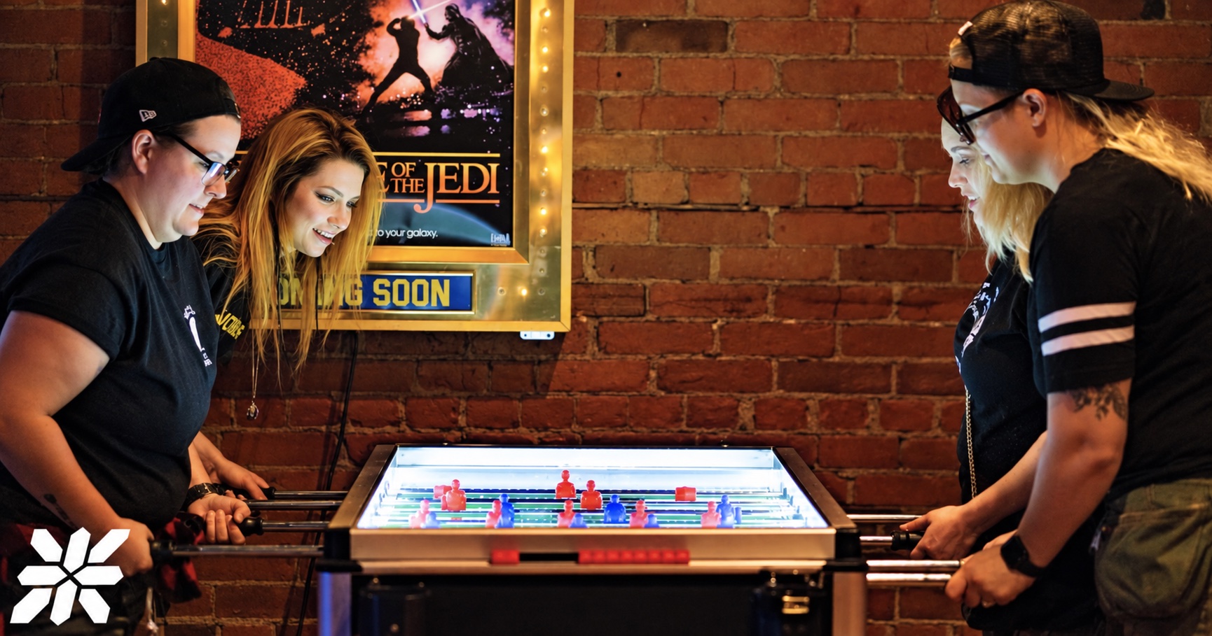 Friends facing off around a glowing tabletop game at ZED*80